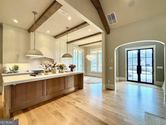 kitchen with visible vents, pendant lighting, light countertops, and a large island with sink