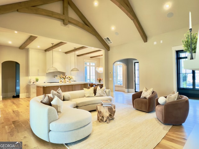 living area with arched walkways, plenty of natural light, visible vents, and light wood-style floors