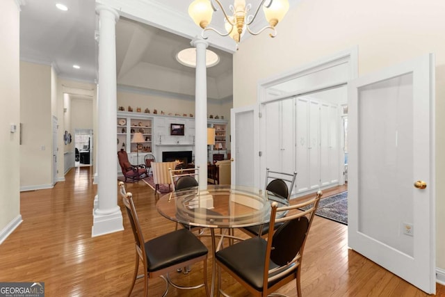 6320 Brady Rd, Murrayville, GA 30564 - dining space with decorative columns, ornamental molding, an inviting chandelier, and light wood-type flooring