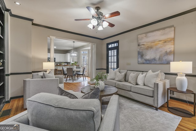 living room featuring visible vents, ornamental molding, ceiling fan, wood finished floors, and ornate columns