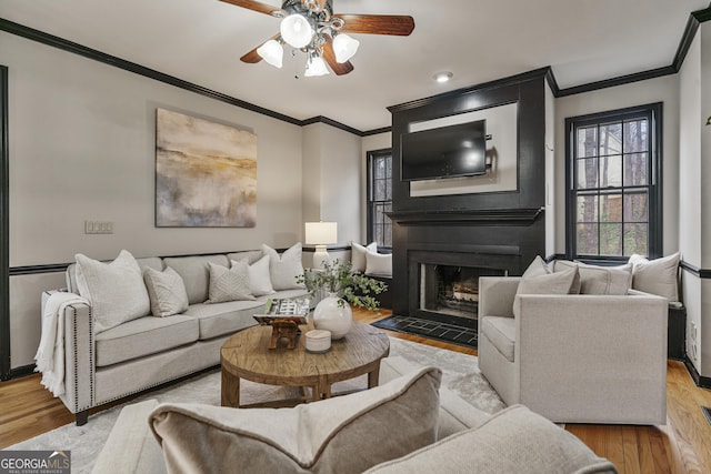 living area with a fireplace, light wood-style flooring, and crown molding