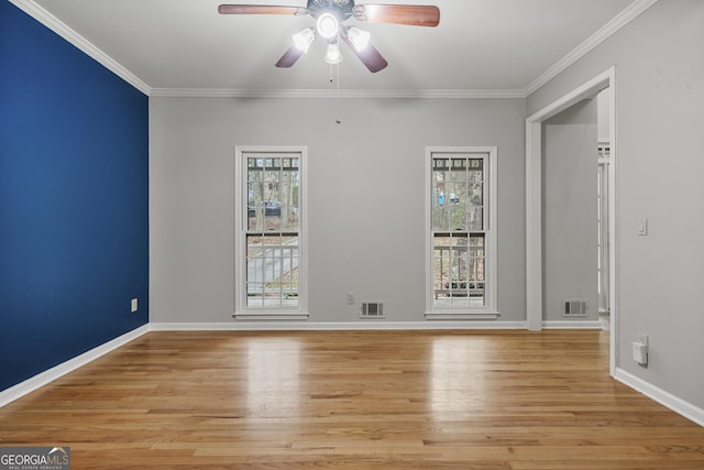 empty room featuring visible vents, baseboards, light wood-style flooring, and crown molding