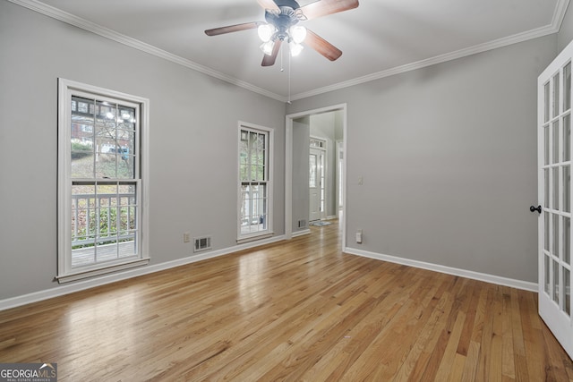 unfurnished room with light wood-style floors, visible vents, crown molding, and baseboards