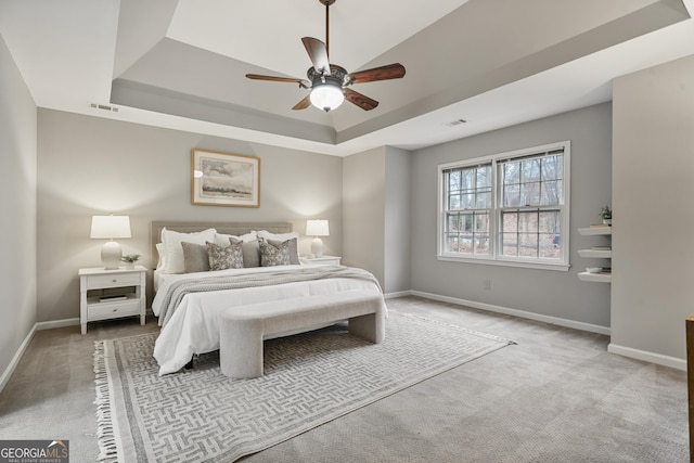 bedroom with light carpet, a raised ceiling, visible vents, and baseboards