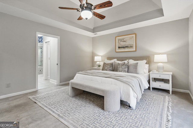 bedroom with baseboards, a tray ceiling, a ceiling fan, and light colored carpet