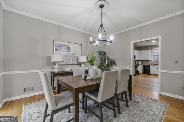 dining space with baseboards, a notable chandelier, visible vents, and light wood-style floors