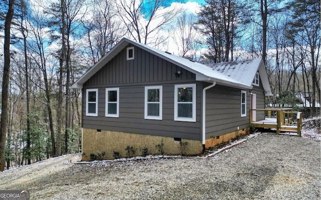 view of property exterior featuring a shingled roof, crawl space, gravel driveway, a wooden deck, and board and batten siding