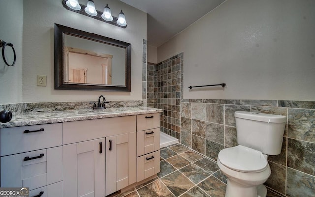 bathroom with tile walls, vanity, and toilet