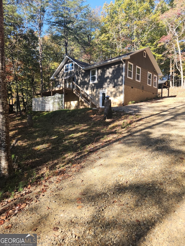 view of home's exterior with crawl space, driveway, stairs, and a wooden deck