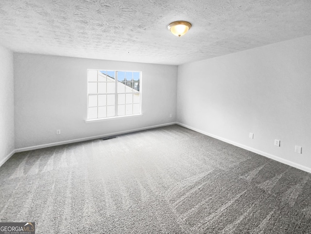 empty room with carpet floors and a textured ceiling