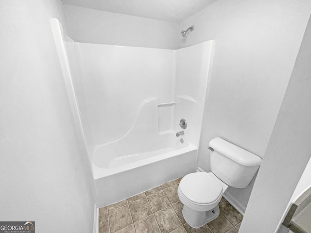 bathroom with tile patterned flooring, tub / shower combination, and toilet