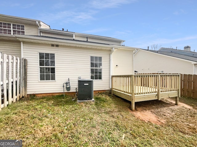 rear view of house featuring cooling unit, a wooden deck, and a lawn