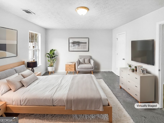 bedroom featuring dark carpet and a textured ceiling