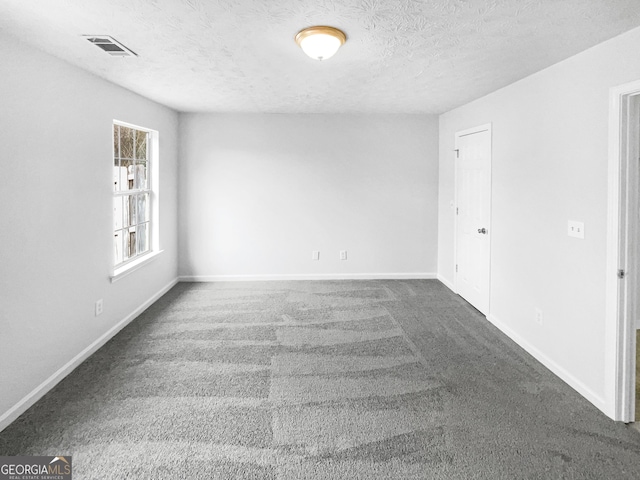 empty room with dark carpet and a textured ceiling