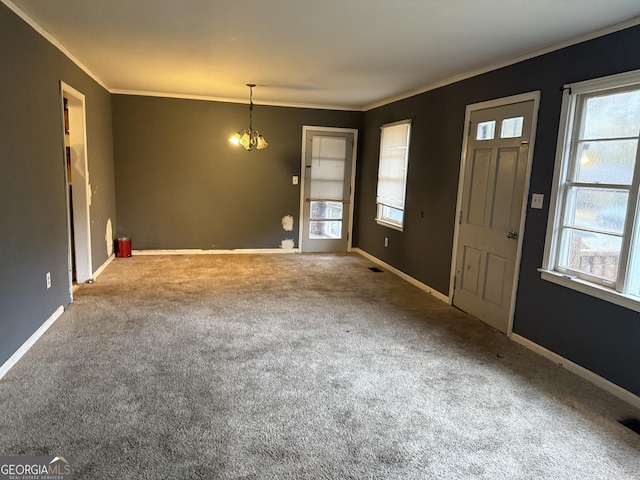 carpeted foyer entrance featuring ornamental molding, plenty of natural light, and a notable chandelier