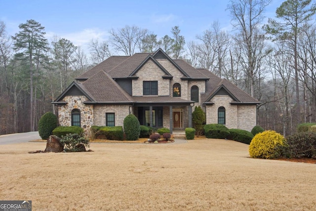 french country style house with a porch and a front lawn