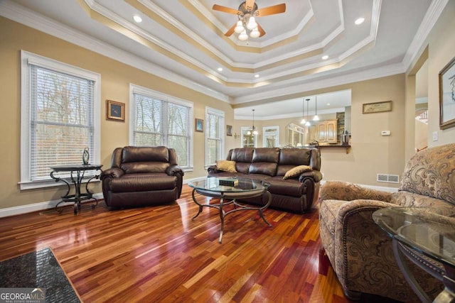 living room with crown molding, a tray ceiling, wood-type flooring, and ceiling fan