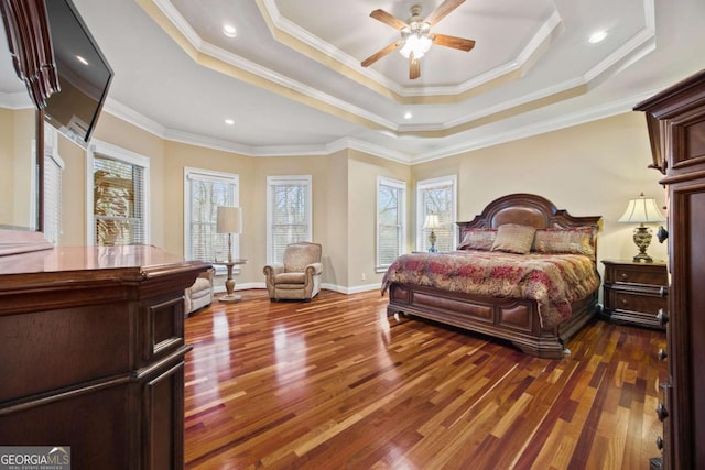 bedroom with a tray ceiling, dark wood-type flooring, ornamental molding, and ceiling fan