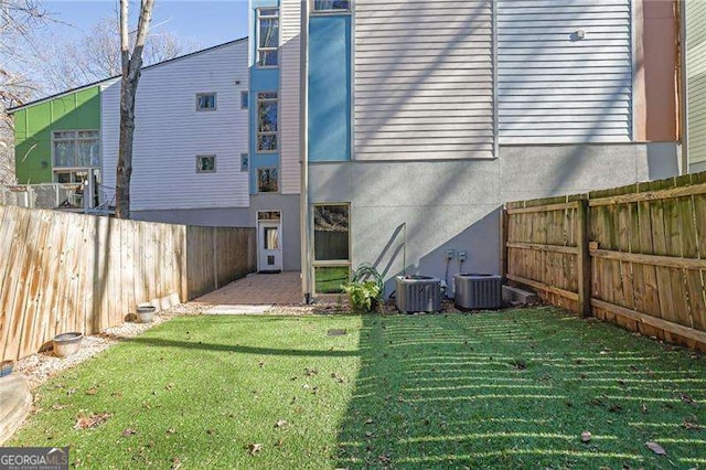 back of house with central AC and a lawn