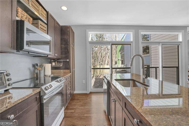 kitchen with stainless steel appliances, dark hardwood / wood-style flooring, light stone countertops, and sink