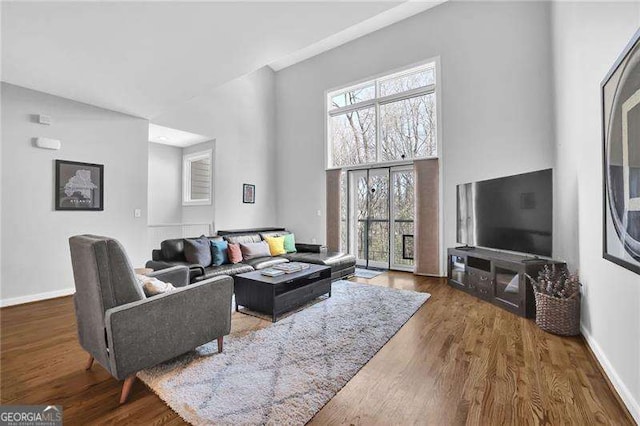 living room with a towering ceiling and dark hardwood / wood-style floors