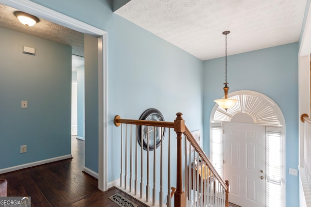 entryway with dark wood-type flooring and a textured ceiling