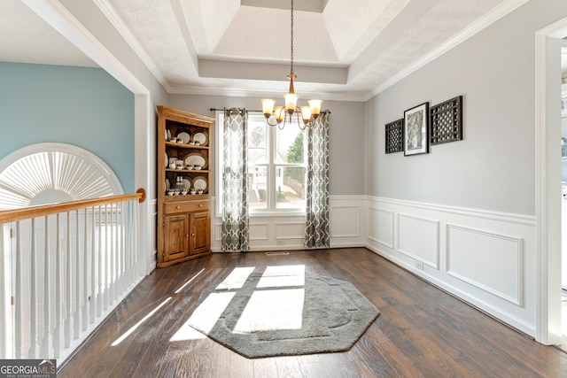 unfurnished dining area with an inviting chandelier, a tray ceiling, and dark wood-type flooring