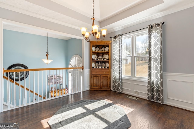 spare room with a raised ceiling, crown molding, a notable chandelier, and dark hardwood / wood-style flooring