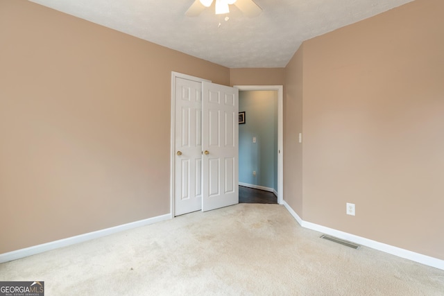 unfurnished bedroom featuring a textured ceiling, carpet floors, and ceiling fan