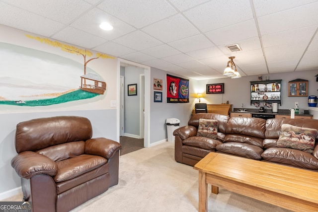 carpeted living room featuring a drop ceiling and bar area