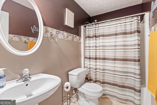 bathroom with a shower with shower curtain, toilet, sink, and a textured ceiling