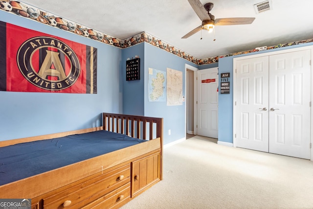 bedroom featuring a textured ceiling, a closet, ceiling fan, and carpet