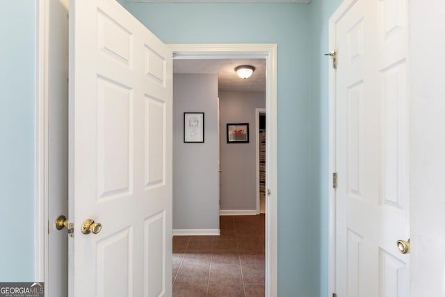 corridor with dark tile patterned flooring and a textured ceiling