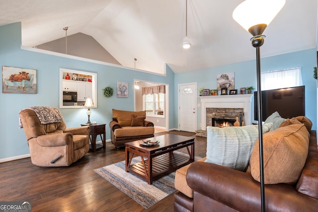 living room with lofted ceiling, a healthy amount of sunlight, dark wood-type flooring, and a fireplace