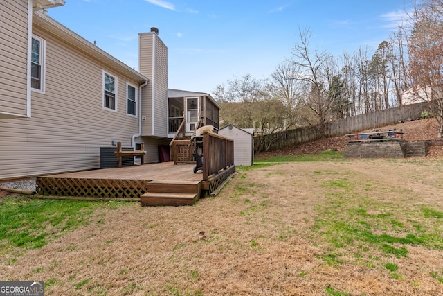 view of yard featuring a wooden deck, a sunroom, and a storage shed