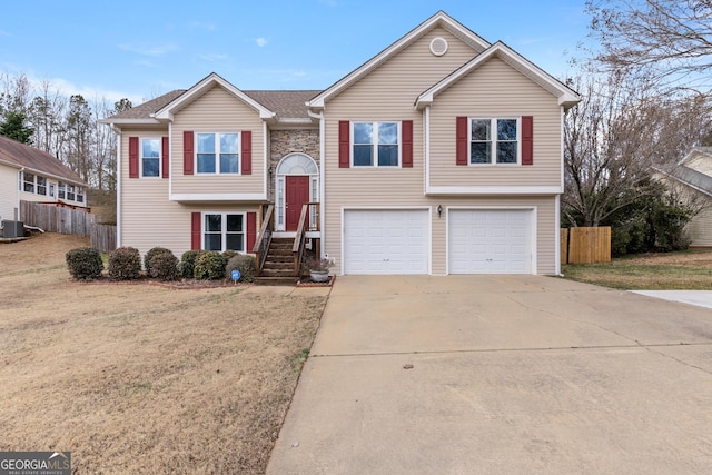 bi-level home with central AC unit, a garage, and a front yard