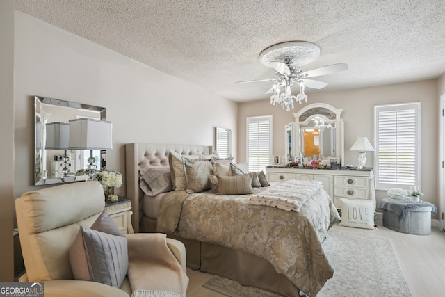 bedroom featuring ceiling fan, multiple windows, and a textured ceiling