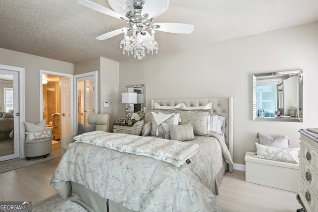 bedroom with ceiling fan, ensuite bath, a textured ceiling, and light hardwood / wood-style flooring