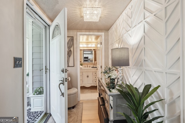 entryway with a chandelier, a textured ceiling, and light hardwood / wood-style floors