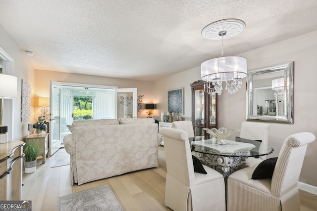 dining space featuring an inviting chandelier, a textured ceiling, and light wood-type flooring