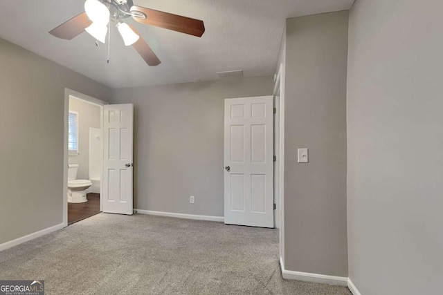 unfurnished bedroom with connected bathroom, light colored carpet, and ceiling fan