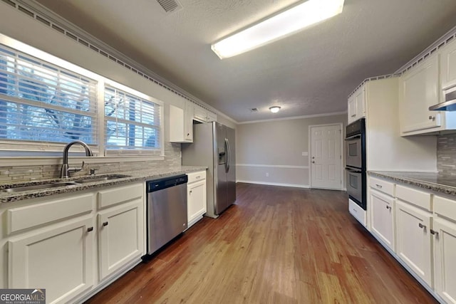 kitchen featuring stainless steel appliances, white cabinetry, and sink