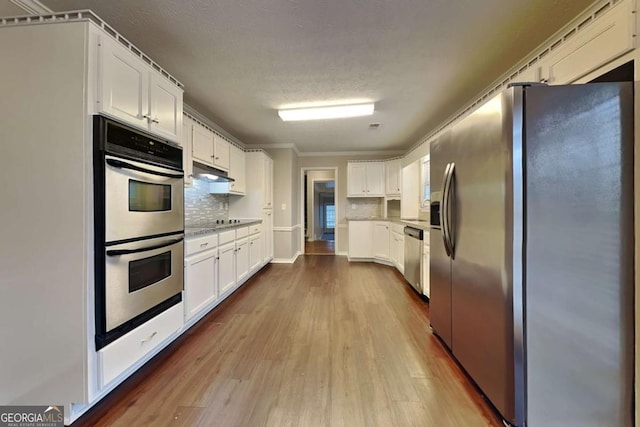 kitchen with backsplash, light hardwood / wood-style flooring, stainless steel appliances, and white cabinets