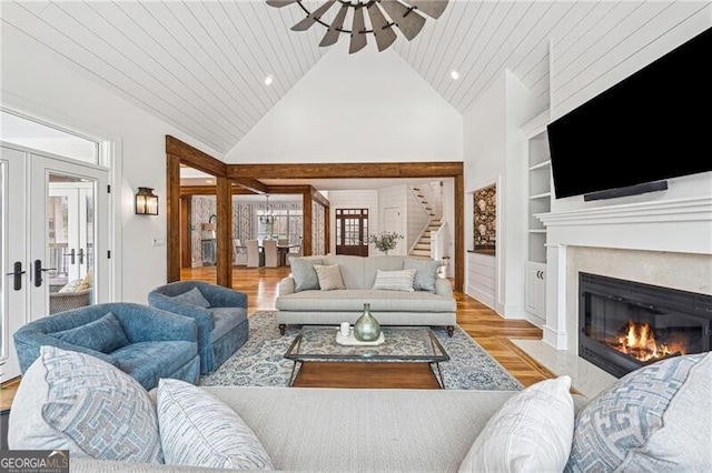 living room featuring built in features, high vaulted ceiling, light hardwood / wood-style flooring, wooden ceiling, and french doors