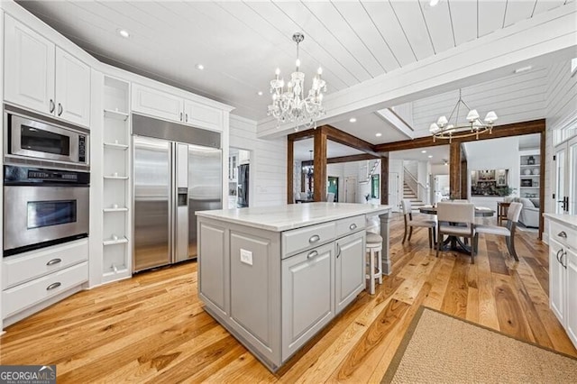 kitchen featuring a notable chandelier, a center island, built in appliances, and white cabinets