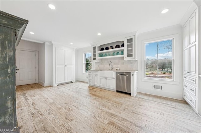 kitchen featuring white cabinetry, decorative backsplash, dishwasher, and light hardwood / wood-style flooring