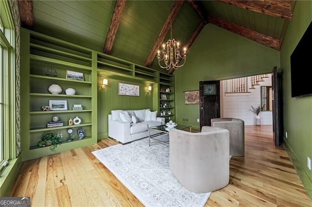 living room featuring built in shelves, vaulted ceiling with beams, wooden ceiling, light wood-type flooring, and a notable chandelier