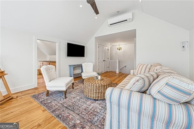 living room featuring hardwood / wood-style flooring, an inviting chandelier, a wall mounted AC, and vaulted ceiling