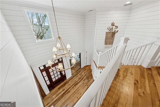 staircase with hardwood / wood-style flooring and a chandelier