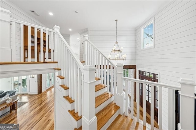 staircase with lofted ceiling, a notable chandelier, and hardwood / wood-style floors